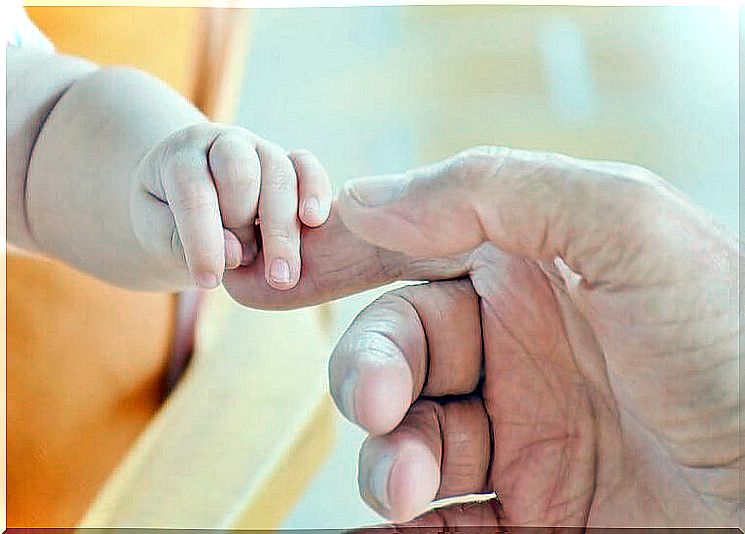 Baby holding a father's finger for grasp reflexes