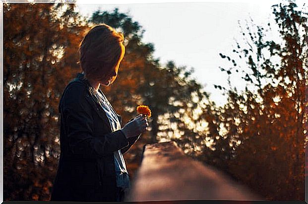 Woman looking at a flower at sunset to overcome hopelessness