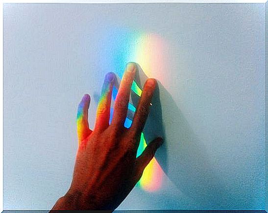 hand touching the rainbow light representing the sensitive person