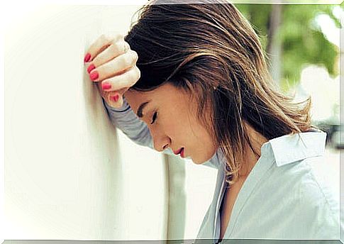 Woman leaning on wall with headache